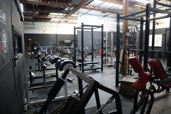 Open Layout showing 1/2 of the gym- GHD's, racks, barbells of every variation, belt squat, TRX, atlas stones, full dumbbell rack