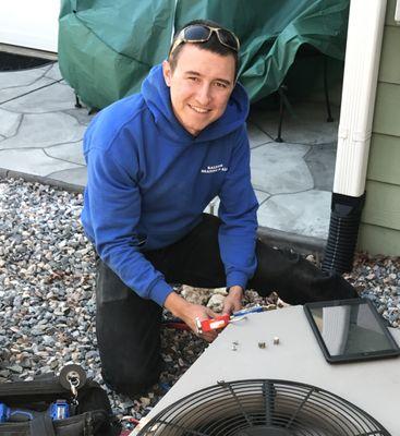 Matt performing spring maintenance on an AC system.