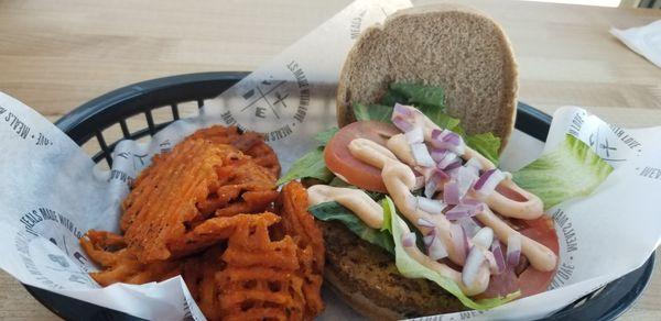 Vegetarian black bean burger on whole wheat bun with side of sweet potato fries.