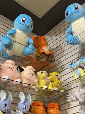 Pokémon plushies on a wall shelf. Visible here are Squirtle, Vulpix, Clefairy, Sandshrew, Raikou, Wartorle, Reshiram.