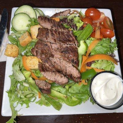 Garden salad topped with steak