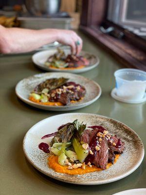 Seared Bavette Steak, Plum Steak Sauce, Duck Fat Roasted Baby Bok Choy, Guajillo Chili Carrot Puree, Toasted Cashews