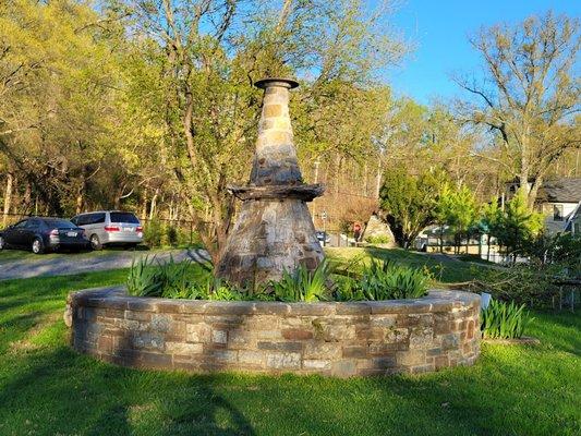 A dilapidated water fountain overgrown with weeds.