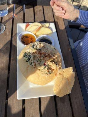 Warm chicken salad in bread bowl with apples and bread slice to dip in balsamic or honey