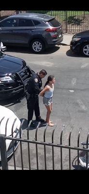 Little girl barefoot on asphalt being handcuffed.