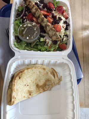 Beautiful fresh Greek salad with a chicken kebab and side of Greek dressing.