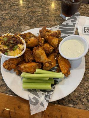 12 fried buffalo hot wings with a side of loaded mashed potatoes.