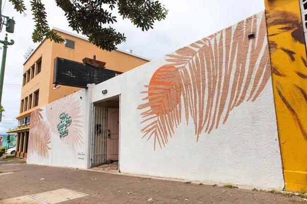 Look for the white wall with palm frond mural