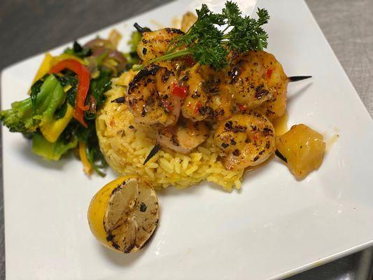 Grilled shrimp with pineapple glaze, yellow rice, and sautéed vegetable medley