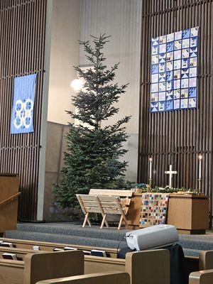 Peaceful Christmas altar with a tree, manger, and quilts symbolizing hope and joy.