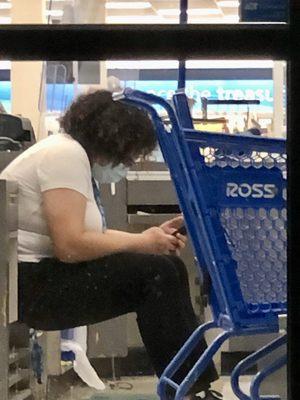 Worker sitting while she should be cleaning the store