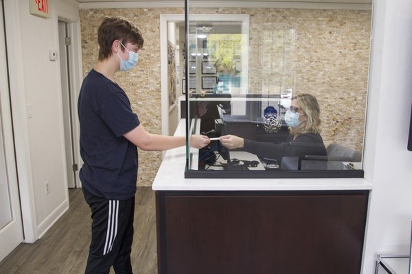 Sue checking a patient out. Our glass barrier at the front desk is another layer of protection to ensure everyone's safety.