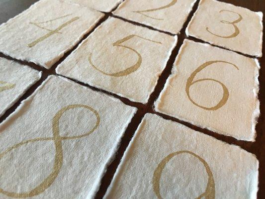 Wedding reception table numbers. Shown: Gold ink calligraphy on handmade paper.