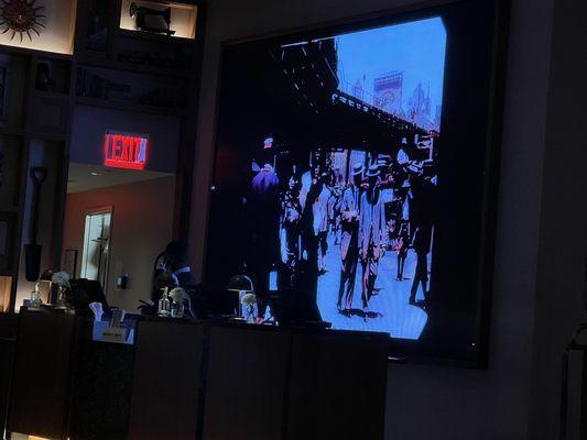 Rerunning video of old NY and people plays behind the front desk. Was able to borrow umbrellas for the rainy day.