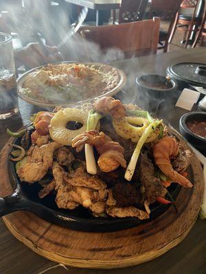 Parillada, served on a sizzling plate. Served with a side of rice, beans, and guacamole.