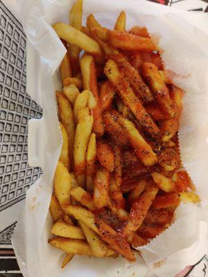 Large french fries with salt pepper and ketchup.