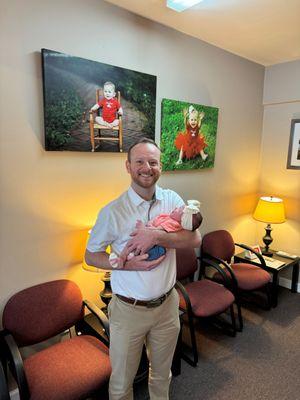 Team member, Tyler, holding his newborn baby girl, Clarke.