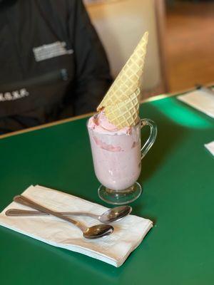 Two scoop strawberry ice cream topped with waffle cone