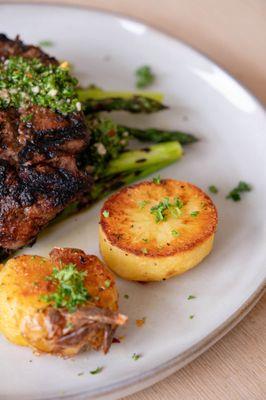 A grilled filet over asparagus with chimichurri and parmesan baby potatoes