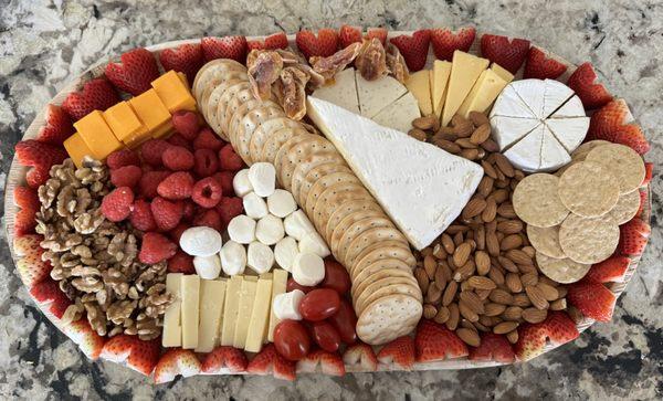 A charcuterie board created for a wedding. The border is made of strawberry hearts. This board was created for 15-20 people.