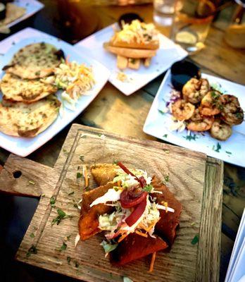 Veggie Pastelitos (empanadas) in front, Shrimp Skewers on right, pupusas and fried yuca from Roxanne's menu