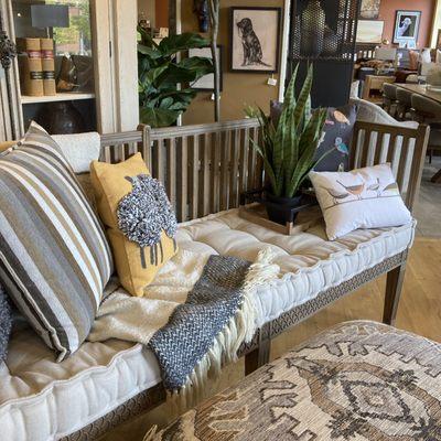 Carved wood bench with cushion with colorful accessories. Renditions Furniture Boise, Idaho