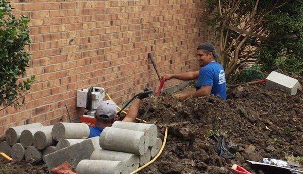 Crew at work digging tunnels to install concrete piers through an exterior breakout