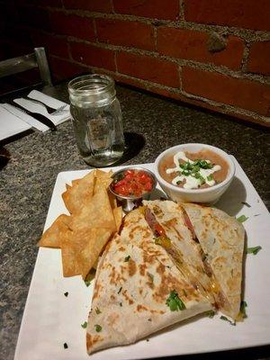 Grilled quesadilla with steak, and a side of homemade refried beans and chips and salsa.