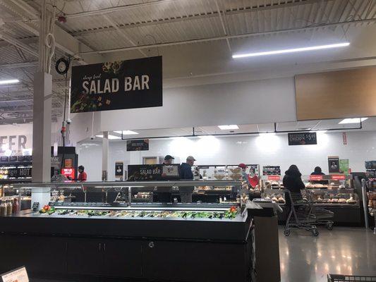 Salad bar with sushi and chicken in the back, the beer and eatery located in the left corner (of this photo)