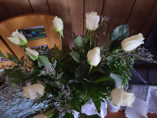 A dozen of white roses with baby's breath in a hand bouquet.