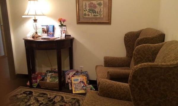 Peaceful waiting room, books to entertain kiddos while you wait, 2 comfy wingback chairs and a georgous demi-moon table border a wool rug.