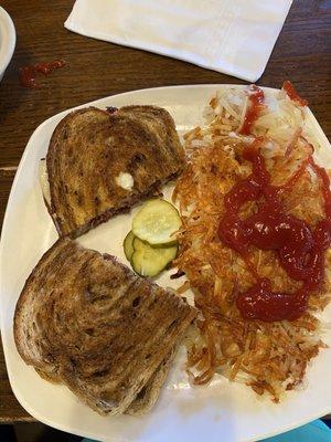 Classic Reuben Sandwich without sauerkraut in photo and side of hash browns with customer added ketchup.