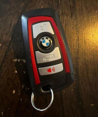 A sleek BMW key fob is featured, showcasing its modern design with a high-quality black and silver finish.