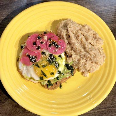 Avocado toast with a sunny side up egg, sesame seeds and house pickled beets and dairy free "cheesy" quinoa grits