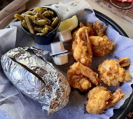 Fried butterfly shrimp with baked potato and green beans.