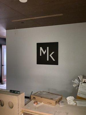 Sign behind reception counter. 30" square. Metal and installed off of the wall for depth.