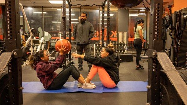 Trainer Alex guides his clients to new heights as they work on their core strength with the help of expert guidance during ball sit ups.