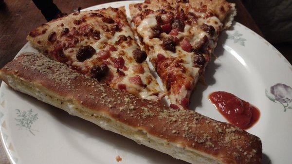 Breadstick with a cut of sausage and bacon pizza