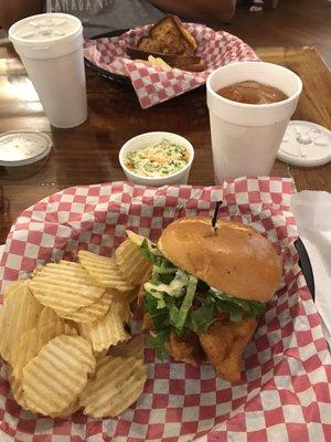 Fish sandwich with chips and coleslaw and grilled cheese in the background.