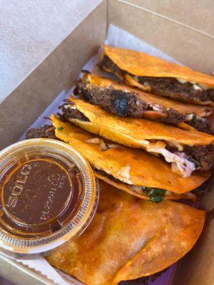 Birria tacos with a side of the dipping consommé sauce.