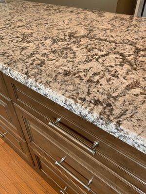 Close up of island cabinets in maple truffle and countertop in Bianca antico.