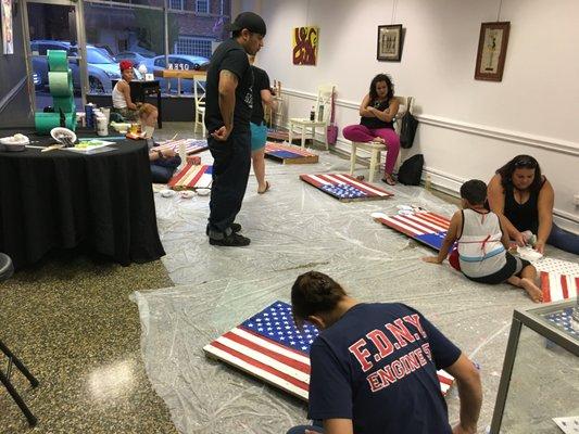 Creatives painting their wood pallet flags for 4th of July at our Pinterest Party