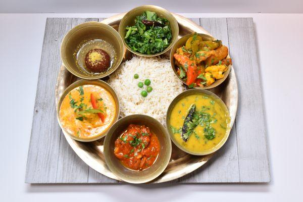 Lunch platter with rice, vegetables, greens, lentils, protein of choice, sweets