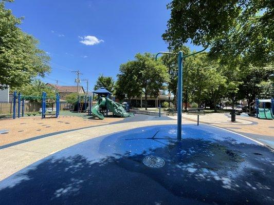 Splash pad and playground equipment. Fieldhouse in the rear.