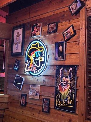 A neon light with many picture frames around it.