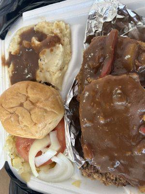 Meatloaf with gravy mashed potatoes cabbage with a tomatoe and onions