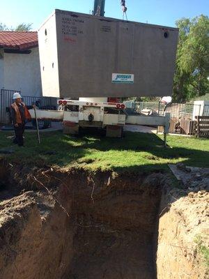 Kurt Bohmer Plumbing Employee's stand by and  watches as A New Septic System is being lowered into the ground !!