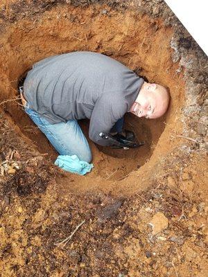 Jeff in a 4 foot hole repairing a pipe near foundation