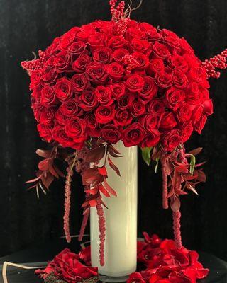 Luxurious red roses with red amaranths and red leaves in a creamy glossy vase