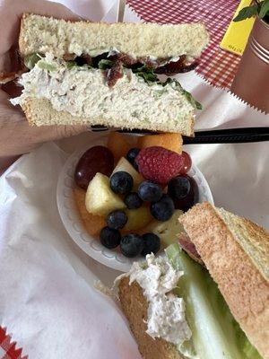 Chicken salad sandwich on toasted sourdough bread with fruit.